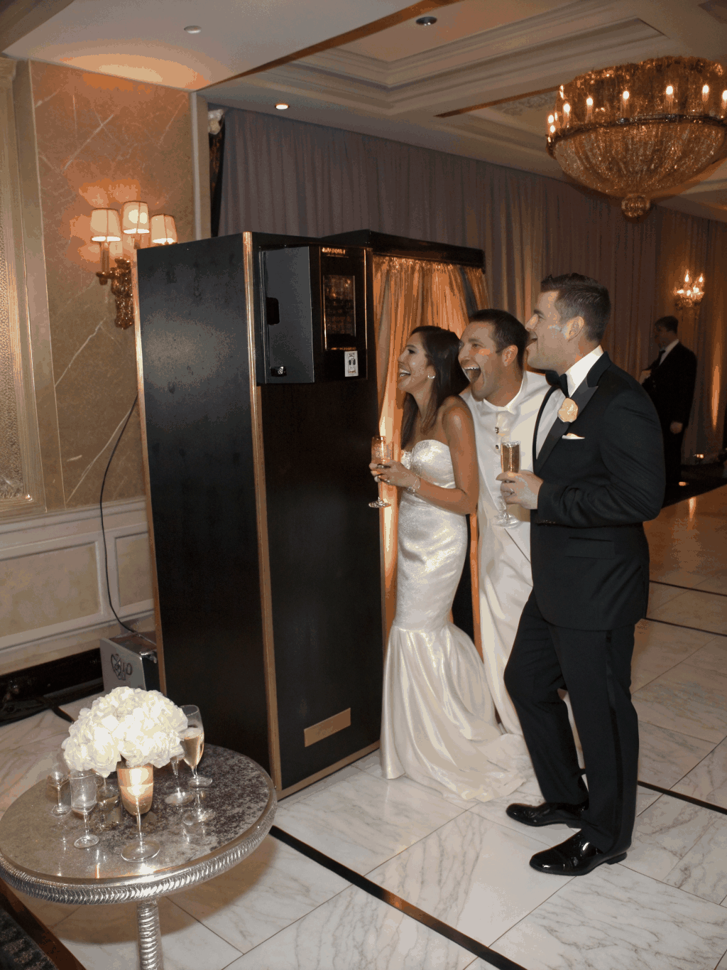 Wedding guests sharing physical photo prints beside champagne cocktails